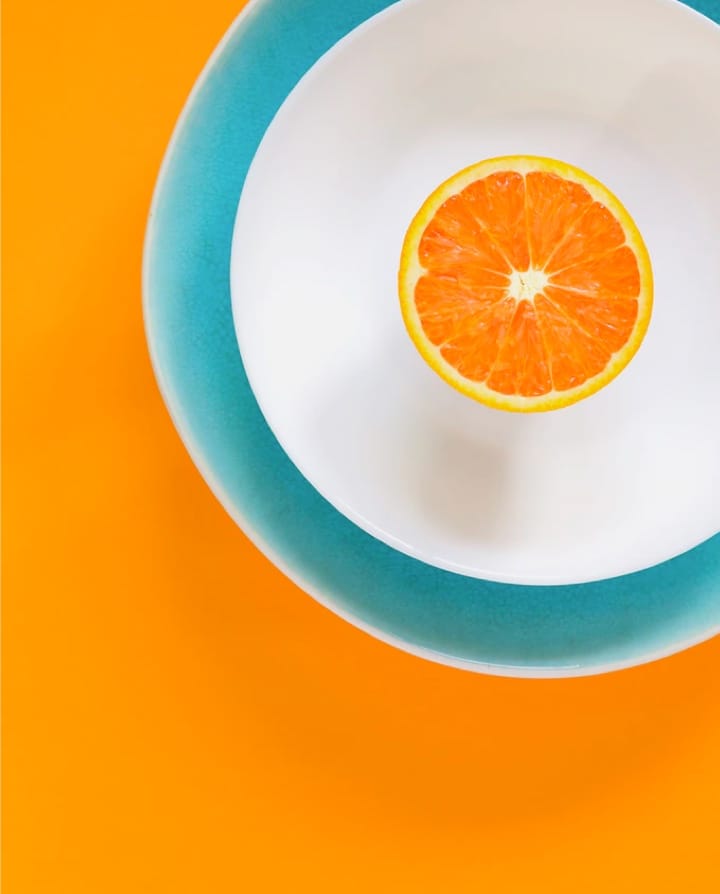 An orange in a plate on a orange background