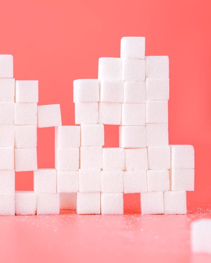 A tower of sugar cubes on a pink background